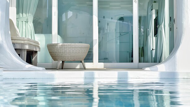 A modern pool area with clear glass doors, a lounge chair, and a small table. - Kenting South Border DeSign Hotel (Hengchun)