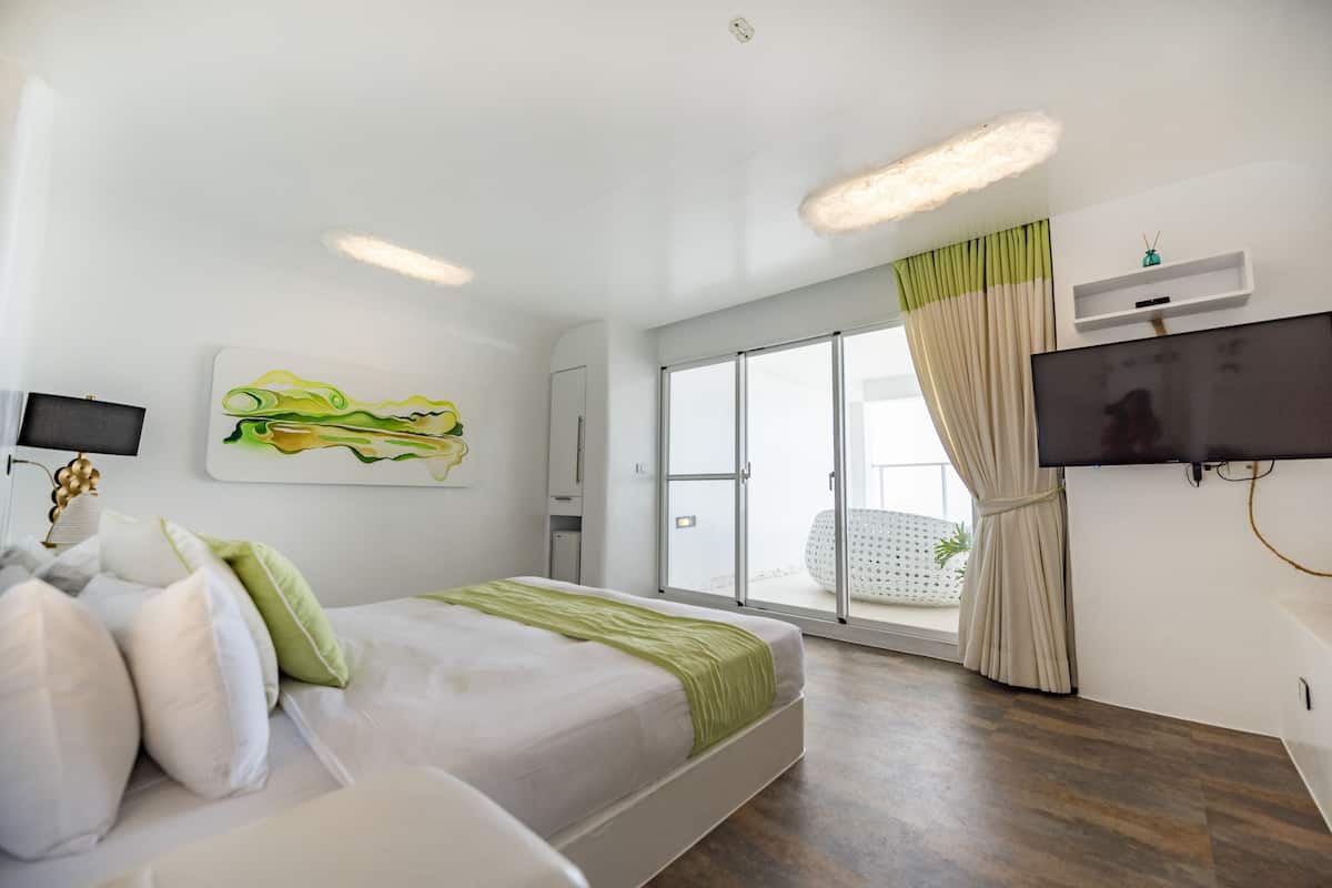 A modern hotel room with a bed, a flat-screen TV, and a large window with curtains.