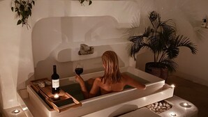 A spa tub with a bottle of wine and candles, surrounded by plants and a pebble-lined area. - Kenting South Border DeSign Hotel (Hengchun)