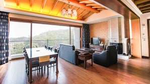 A spacious living area with a dining table, sofas, and a fireplace. - PineRidge Resort (Goseong)