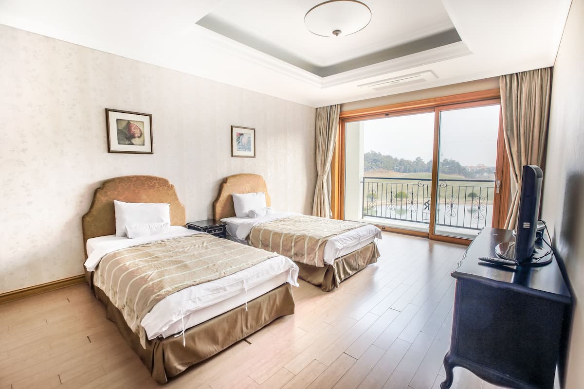 A hotel room with two beds, a TV, and a balcony with a view.