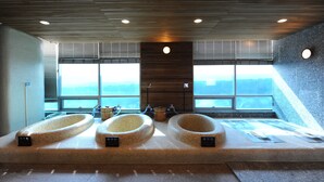 A modern spa area with three large, freestanding tubs under a sloped ceiling with recessed lighting. - PineRidge Resort (Goseong)