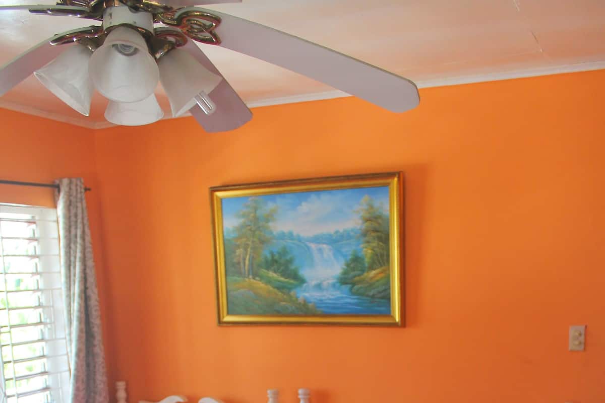 A bedroom with a large bed, white headboard, and a ceiling fan.