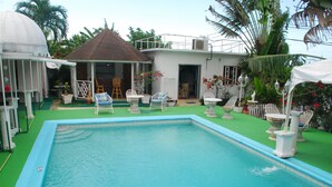 Una piscina con sillas de descanso y un porche cubierto.