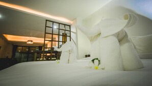 A hotel room with a neatly made bed, a large window, and a modern interior design.
