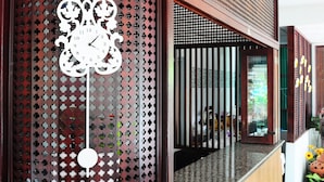 A reception area with a wooden reception desk, a decorative clock, and a view of the interior through a glass partition. - Choktawee Smile (Chiang Mai)