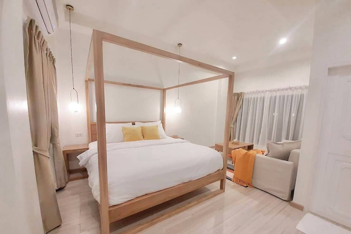 A modern bedroom with a four-poster bed, a bedside table, a chair, and a small table.