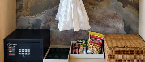 A robe hanging on a wall, a microwave, a box of snacks, and a wicker basket.