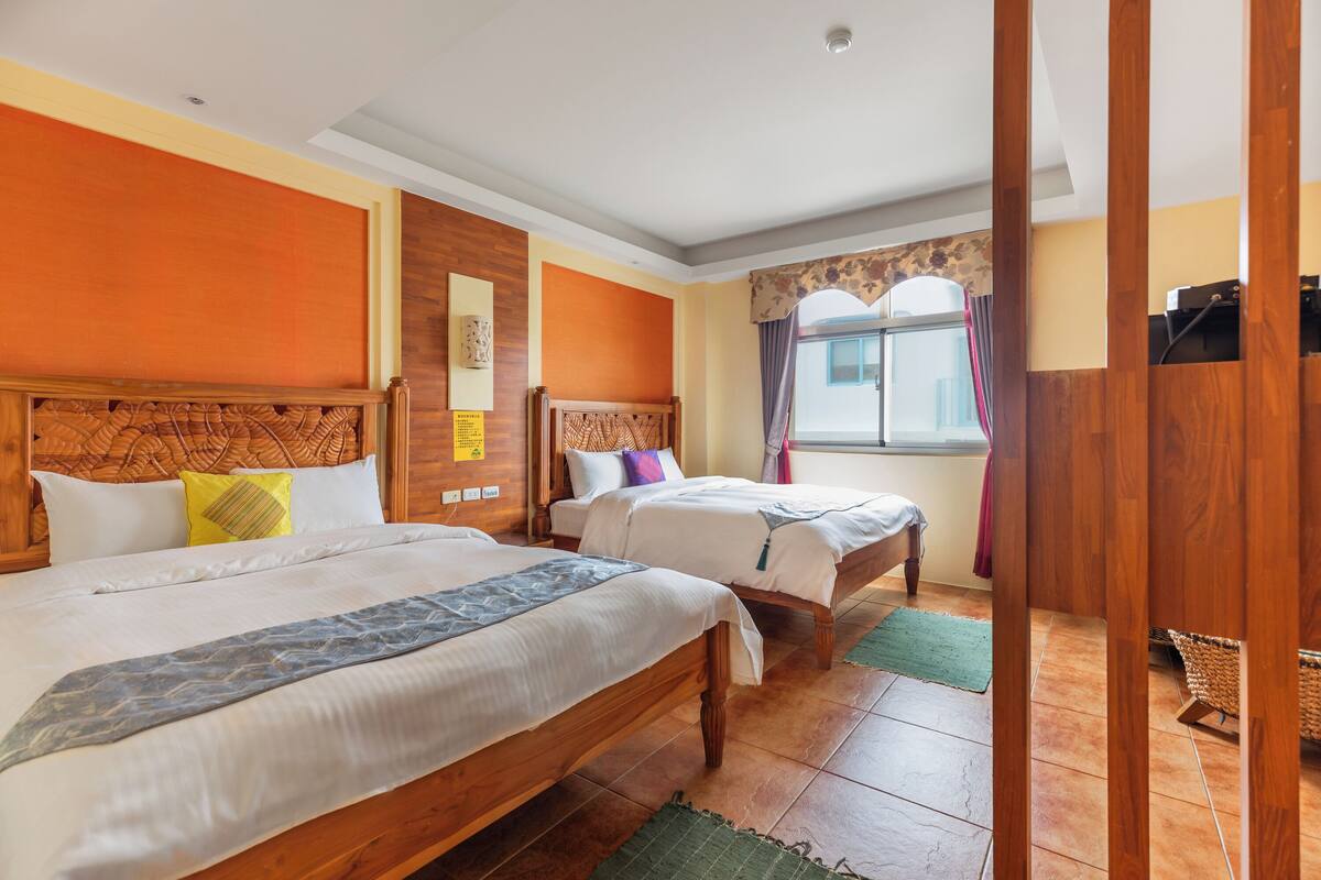 A hotel room with two wooden beds, a large window with curtains, and a view of the city.