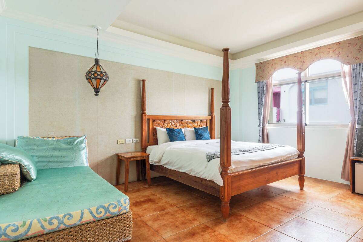 A four-poster bed with a wooden headboard and footboard, a bedside table, and a hanging lantern.