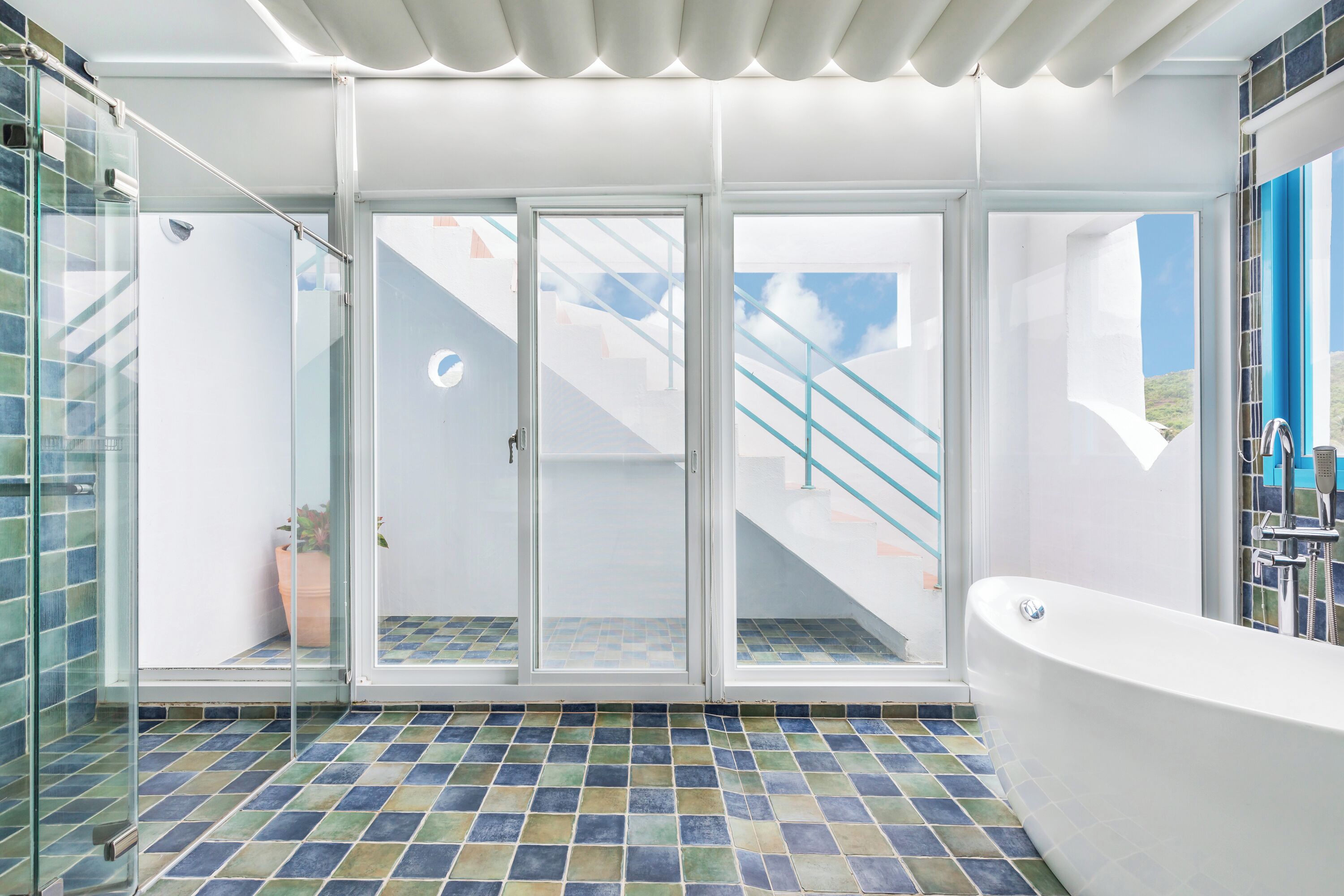 Uma casa de banho moderna com chuveiro de vidro, banheira branca e chão em mosaico.