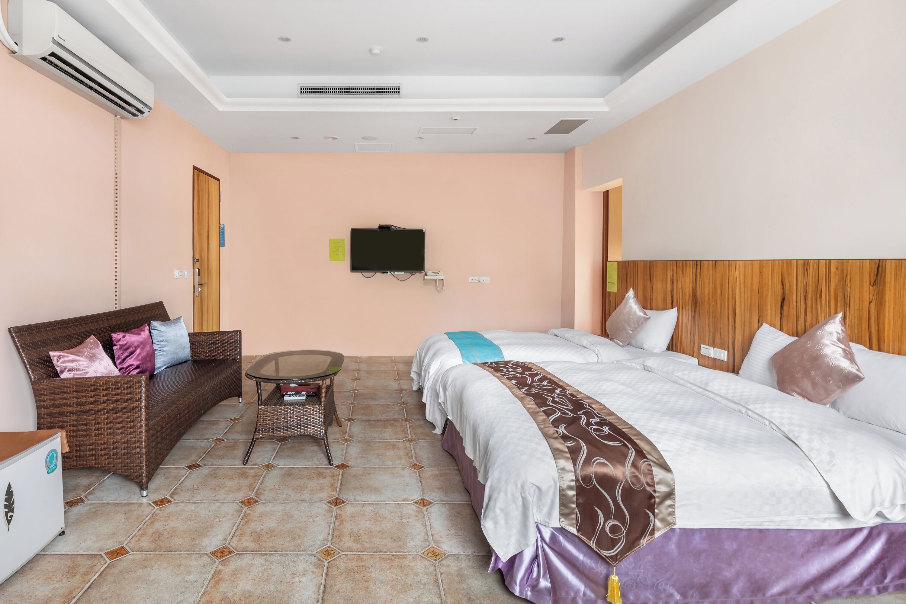 Una habitación de hotel con una cama, un sofá, una mesita y un televisor en la pared.