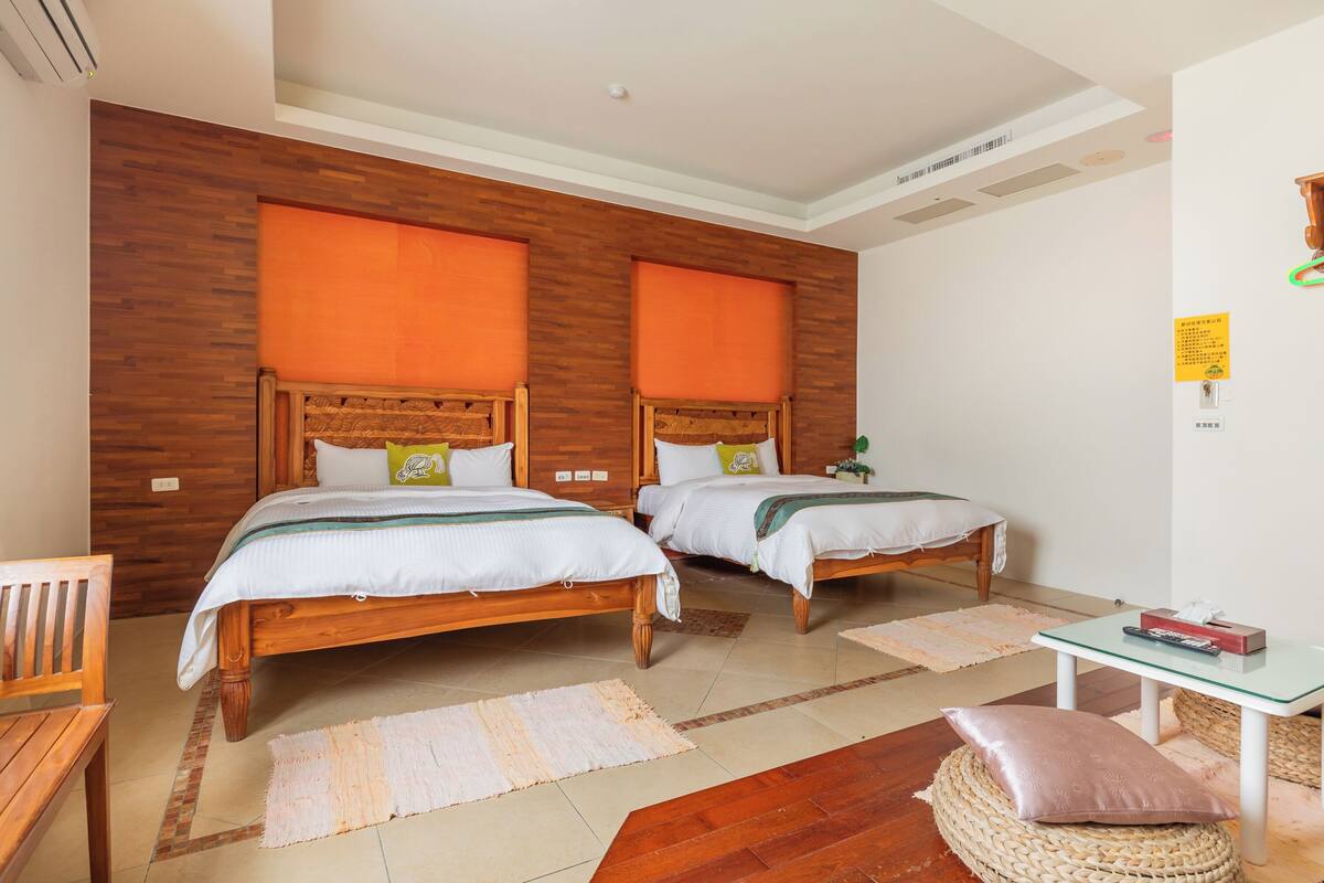A room with two wooden beds, a small table, and a chair.