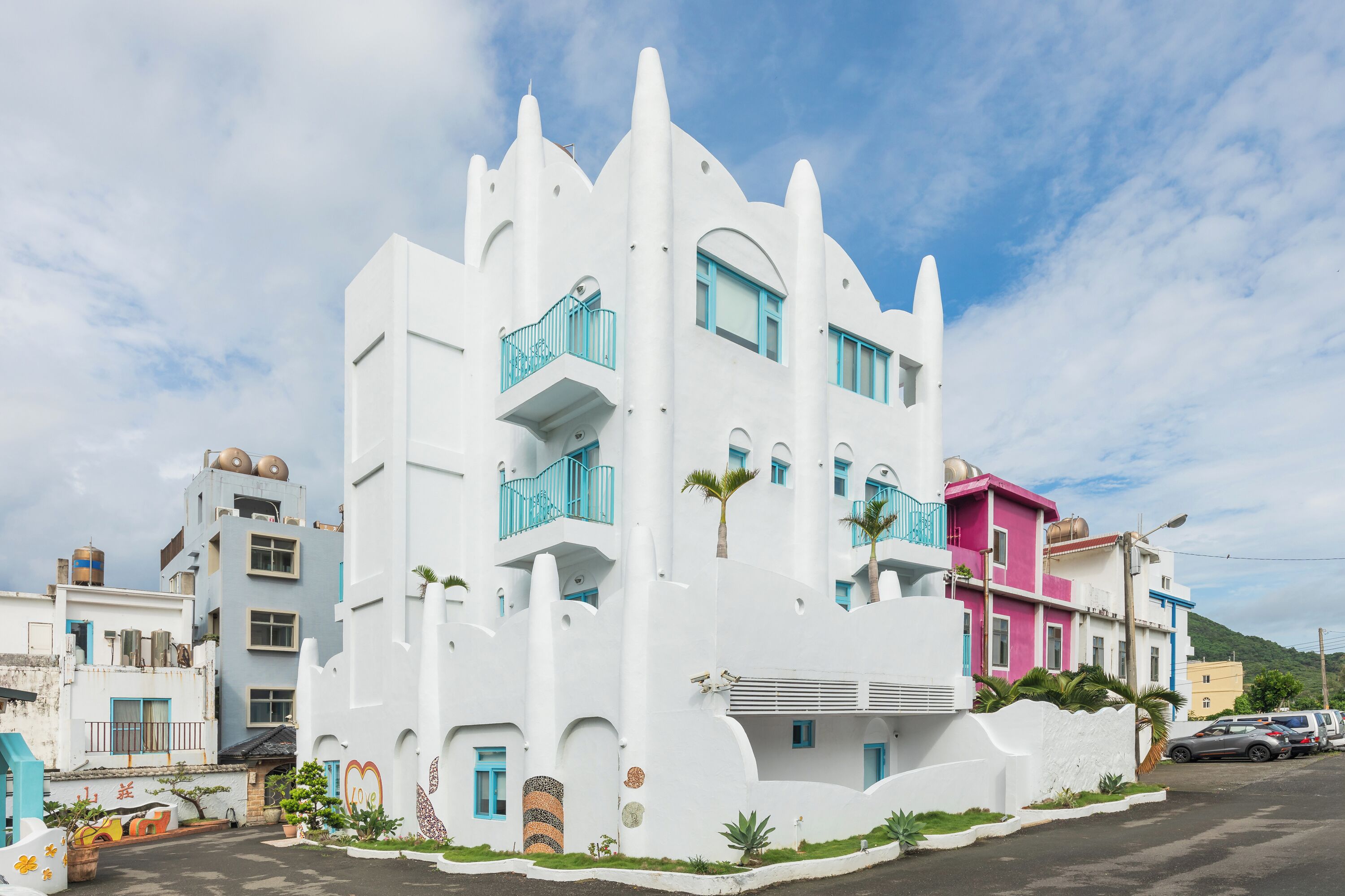 A white building with balconies and a parking lot.