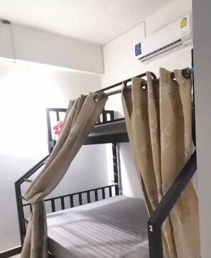 A bunk bed with curtains, a window, and an air conditioning unit.