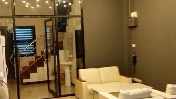 A modern living room with a white sofa, a glass partition, and a staircase leading to another level. - Chiangmai Gate Capsule Hostel (Chiang Mai)