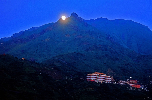 A mountain with a lit building at its base.