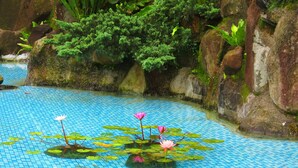 A koi pond with water lilies and fish, surrounded by rocks and greenery. - Formosa Arcadian Villa (New Taipei City)