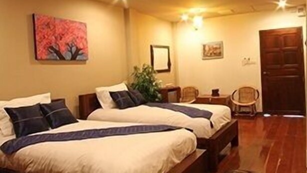 A hotel room with two beds, wooden flooring, a painting on the wall, and a door. - ThongRan's house (Chiang Mai)