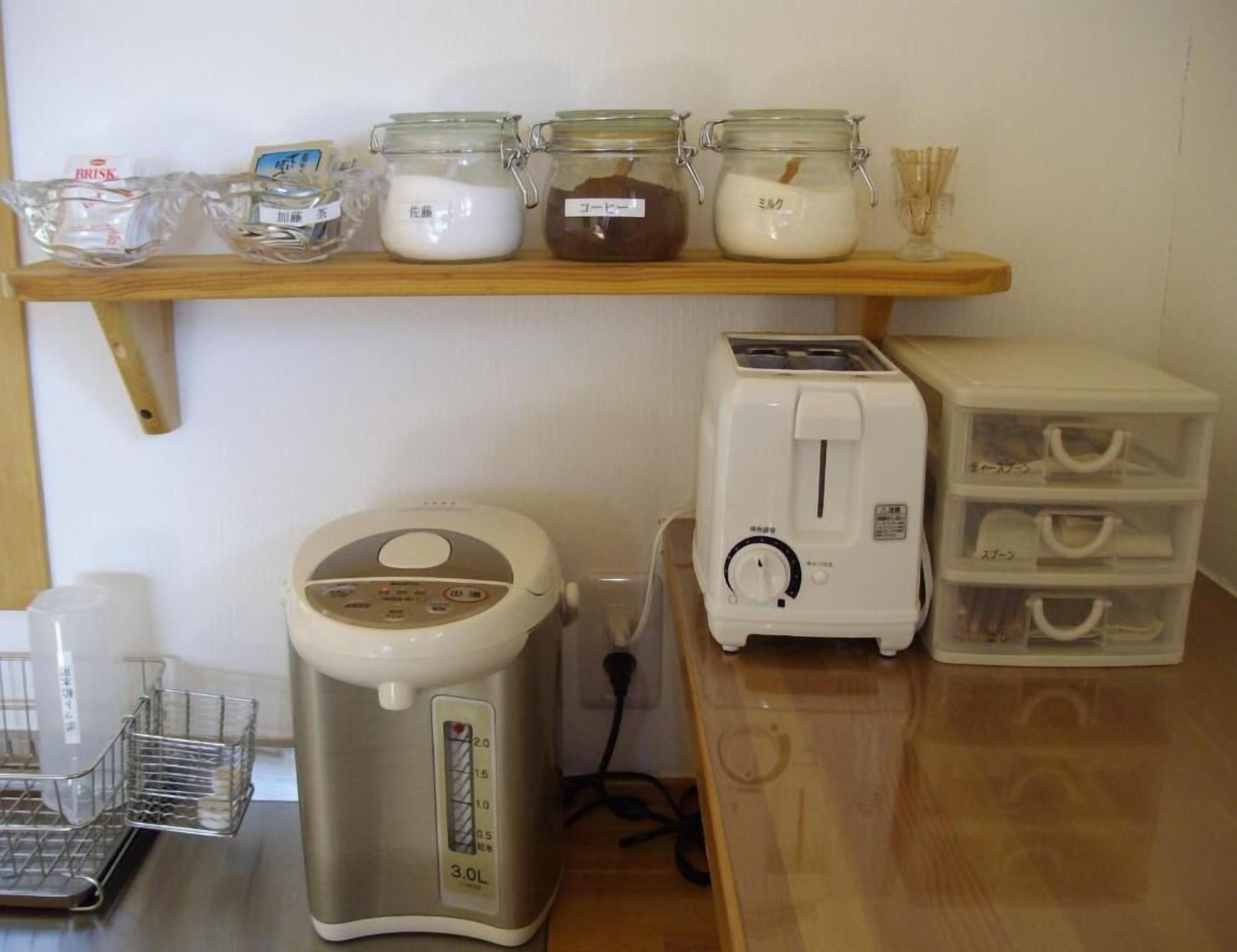 A kitchen with a bread maker, a toaster, and a shelf with jars of condiments.
