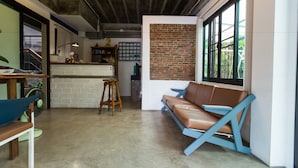 A modern interior with a brick accent wall, a leather sofa, and a wooden bar area. - Plern Plern Bed and Bike (Chiang Mai)
