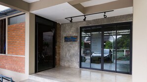 A modern building entrance with a glass door, a sign for 'Room For Rent', and a brick wall. - Plern Plern Bed and Bike (Chiang Mai)