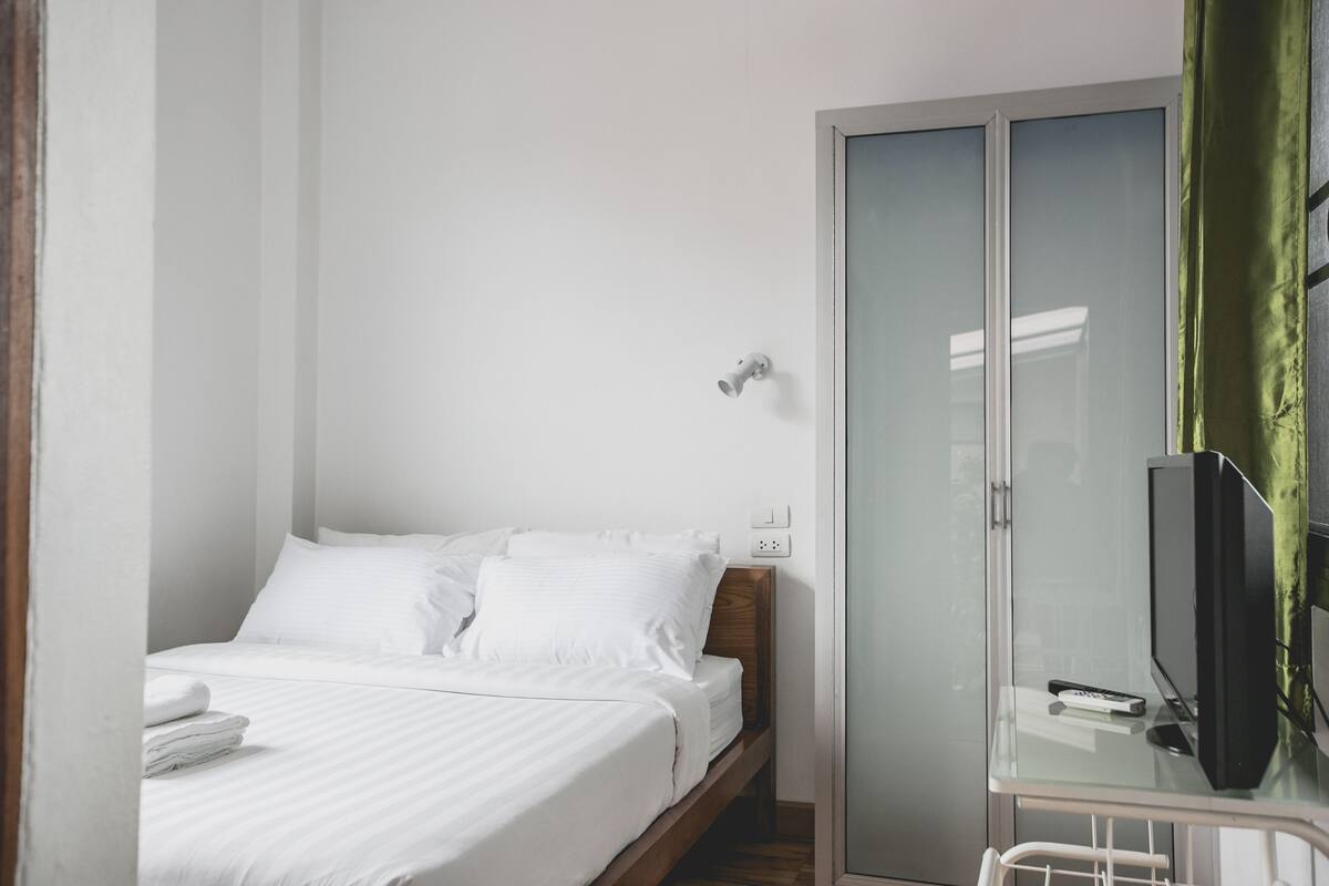 Une chambre d’hôtel avec un lit, une armoire et un téléviseur.
