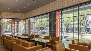 Un ristorante con ampie vetrate, sedute in pelle e vista sulla strada.