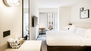 Camera d'albergo con un letto grande, una scrivania con una sedia, una TV e uno specchio. C'è una finestra con vista sull'esterno.