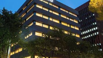 A multi-story building with the 'amba' logo, surrounded by trees.