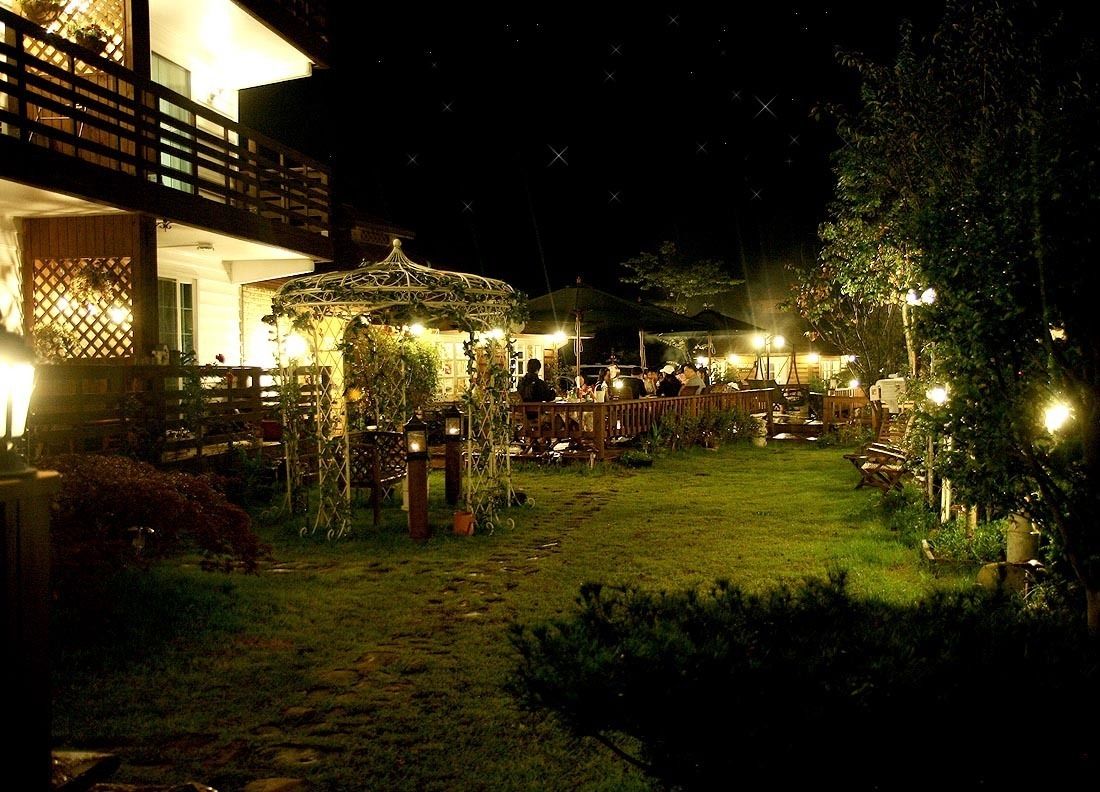 Un jardín exterior con un pabellón, zonas de estar y un sendero.