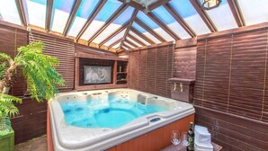 A hot tub with a wooden surround, a television screen, and a bottle of wine. - Spa Pension Basso (Sokcho)
