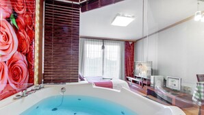 A modern bathroom with a large bathtub, a mirror, and a vanity with a sink. - Spa Pension Basso (Sokcho)