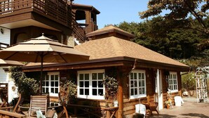 A wooden lodge with a welcoming entrance, large windows, and outdoor seating. - Spa Pension Basso (Sokcho)