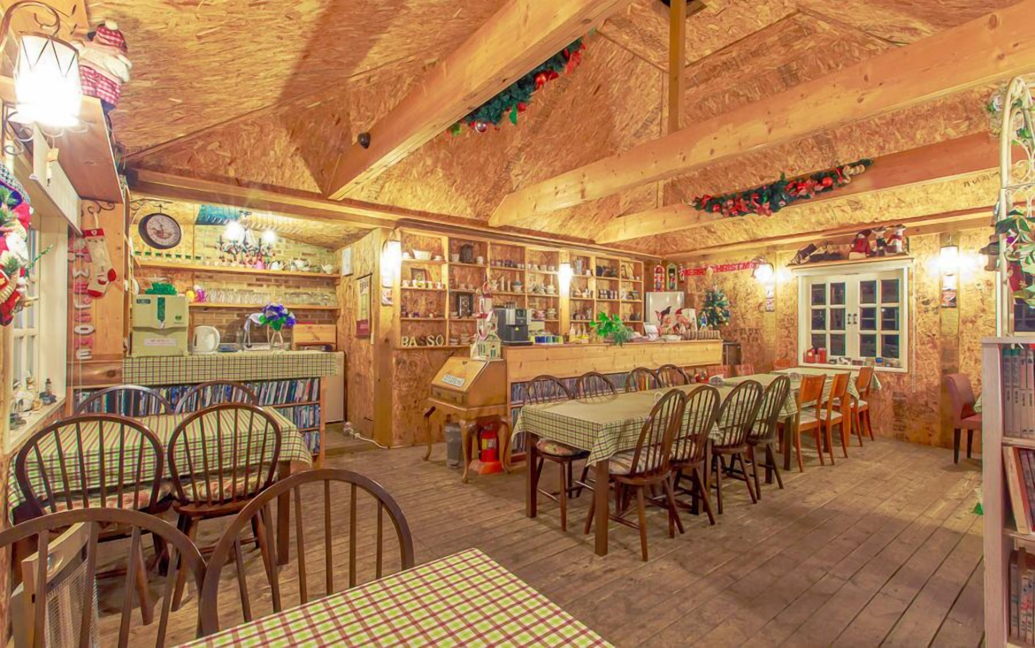 Un café rústico y acogedor con interiores de madera, una barra y diferentes opciones de asientos, incluyendo mesas y sillas.