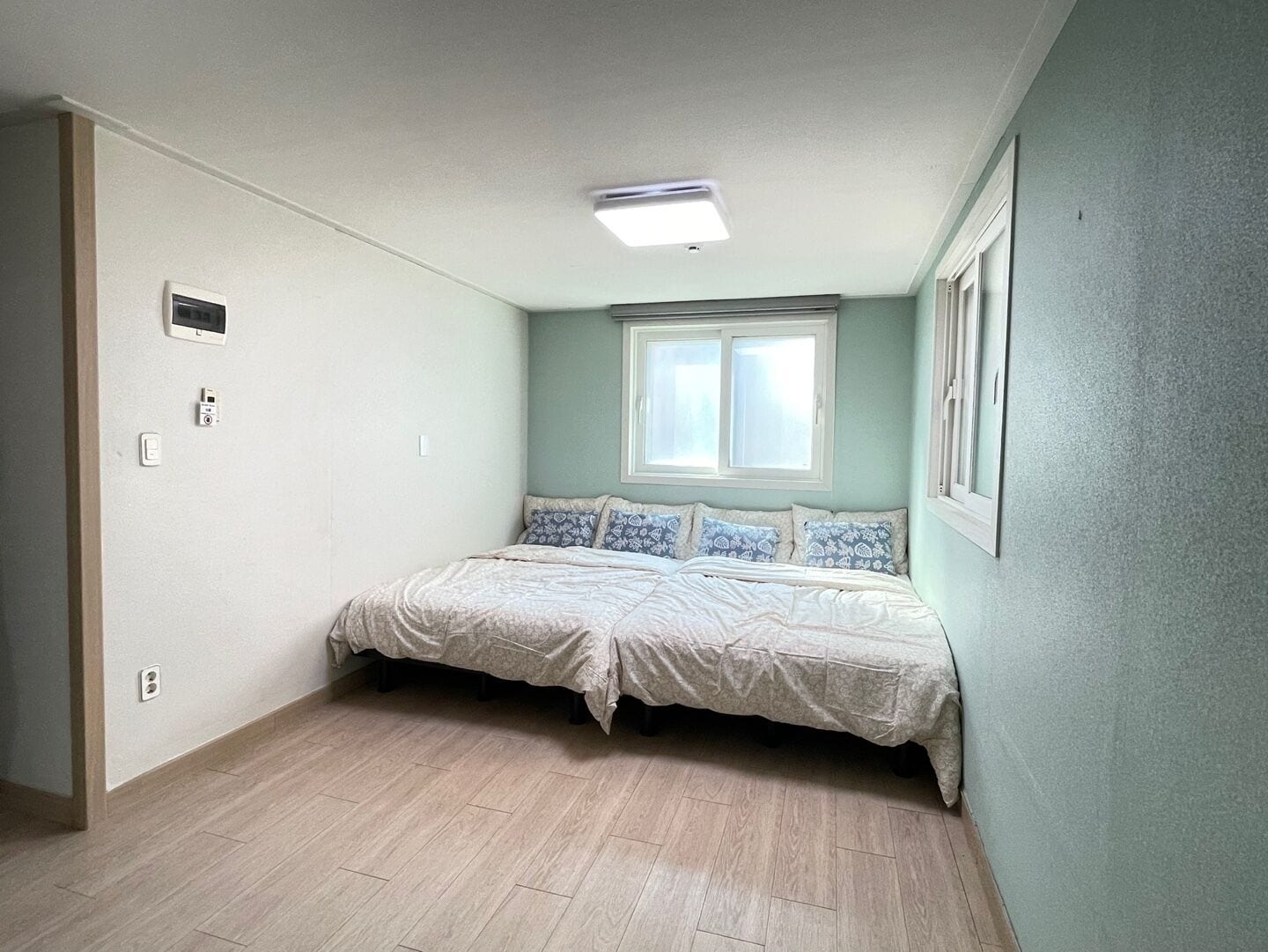 Un dormitorio con cama, ventana y lámpara en el techo.
