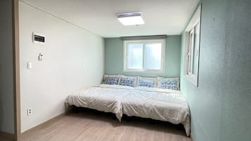 Un dormitorio con cama, ventana y lámpara en el techo.