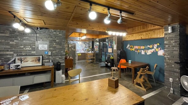 A cozy interior with wooden ceilings, a kitchen area, and a dining space. - Twin Rabbit Guesthouse (Seoul)