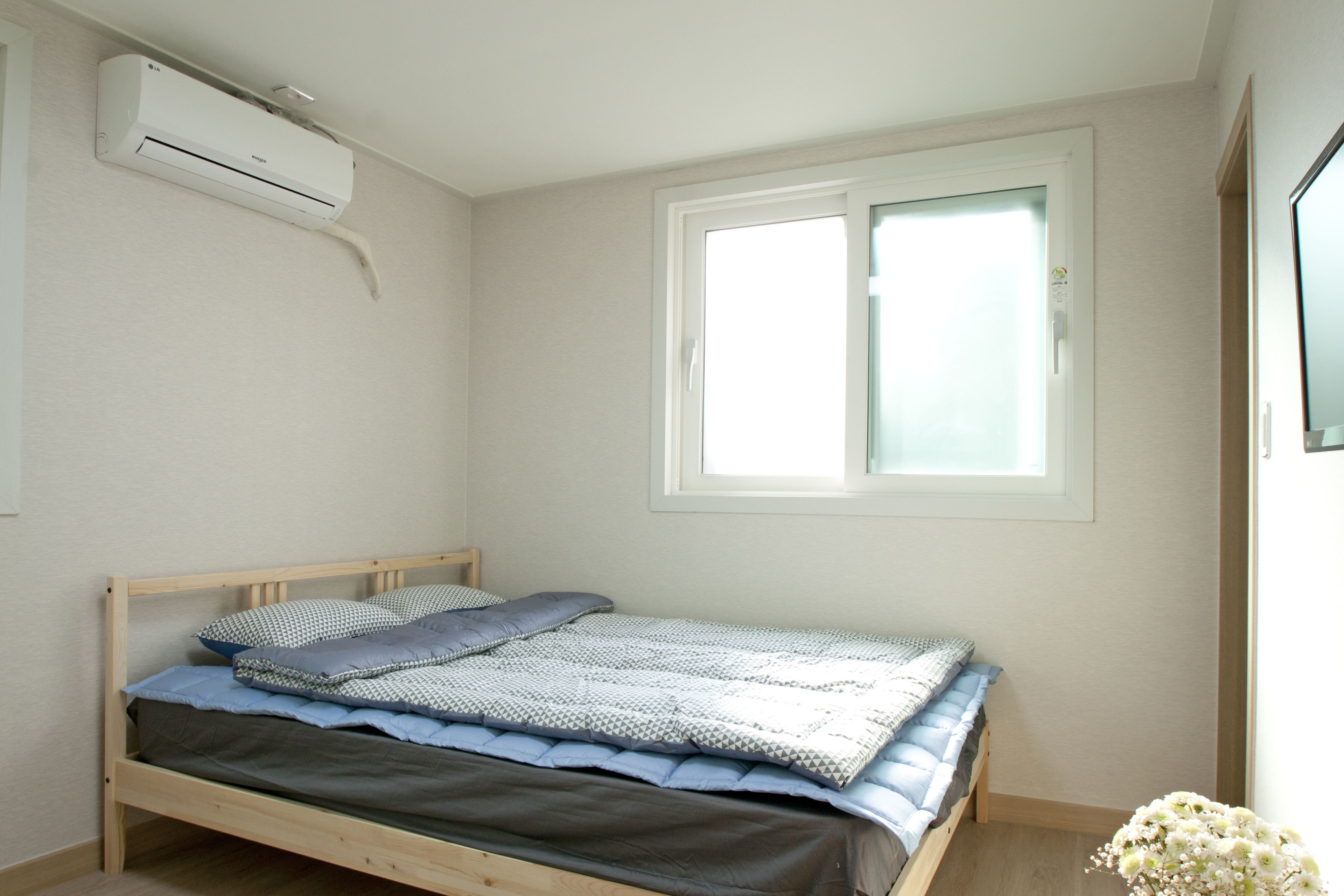 Un dormitorio con cama, ventana y equipo de aire acondicionado.