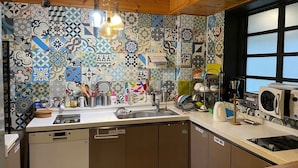 A kitchen with a tiled backsplash, a sink, a stove, and various kitchen appliances. - Twin Rabbit Guesthouse (Seoul)