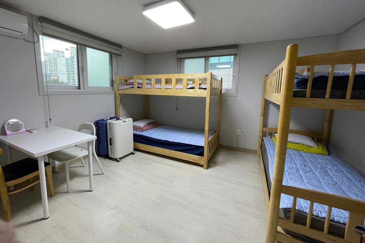 A room with bunk beds, a desk, a chair, and a suitcase.
