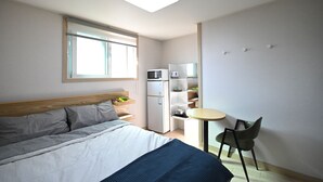 A bedroom with a bed, a small kitchenette, a window, and a chair. - Twin Rabbit Guesthouse (Seoul)