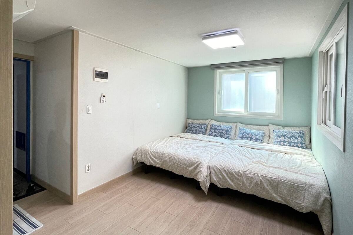 A bedroom with a bed, a window, and a door.