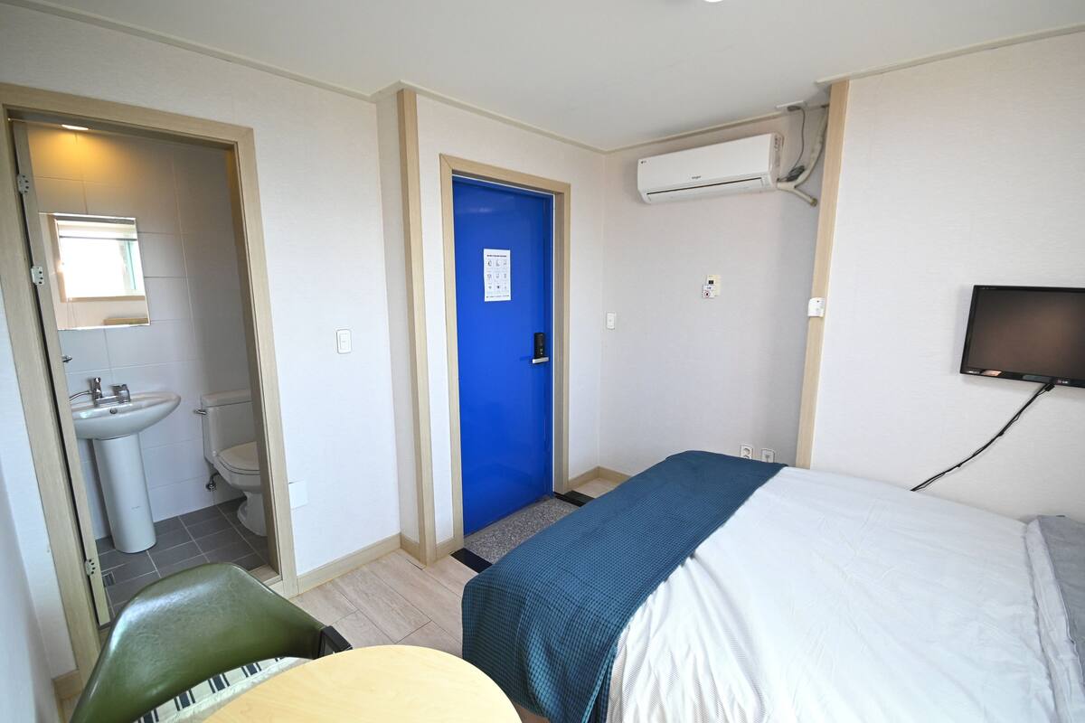 A hotel room with a bed, a chair, a sink, and a toilet.