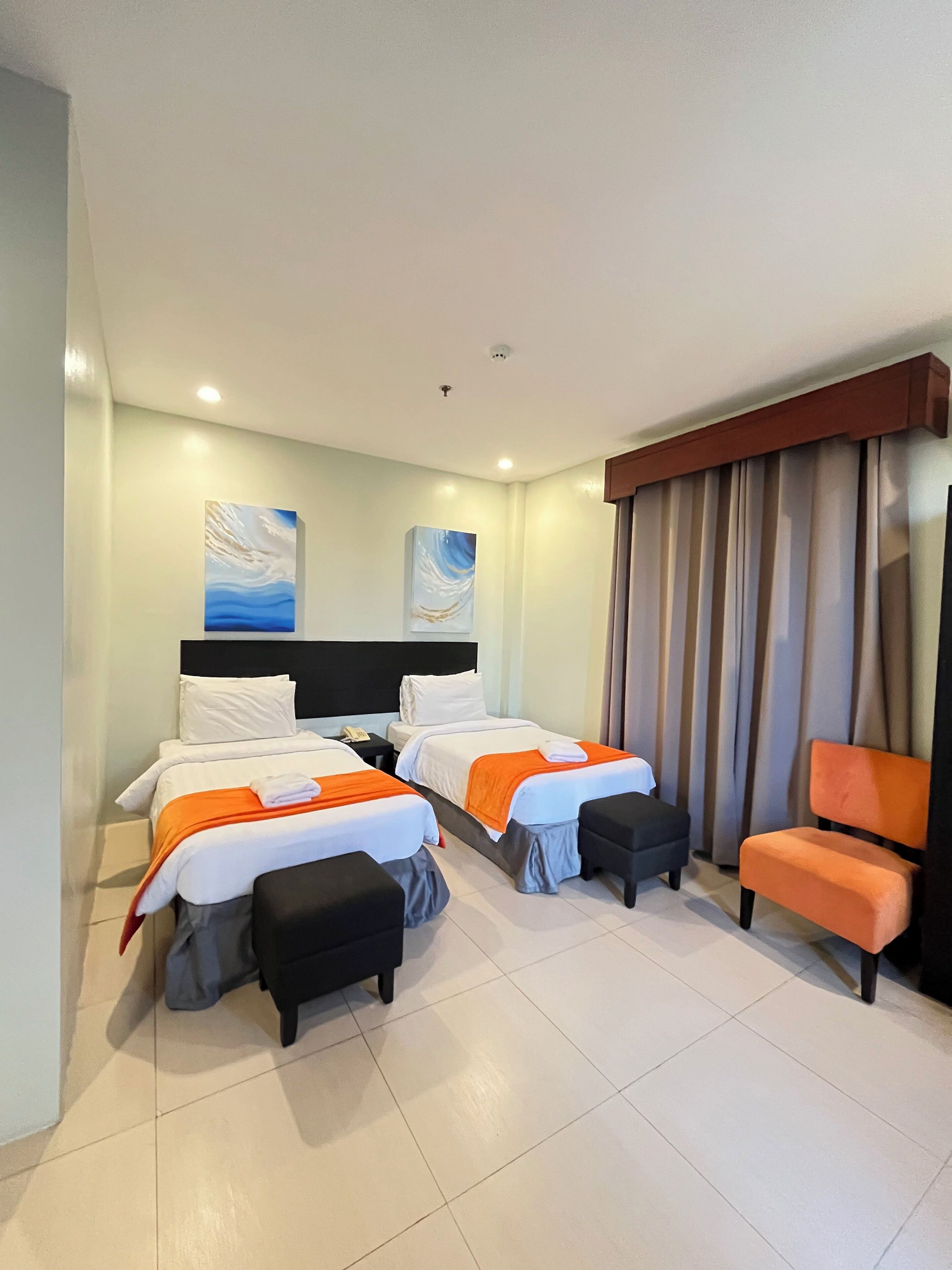 Habitación de hotel con dos camas, una silla y una mesita.