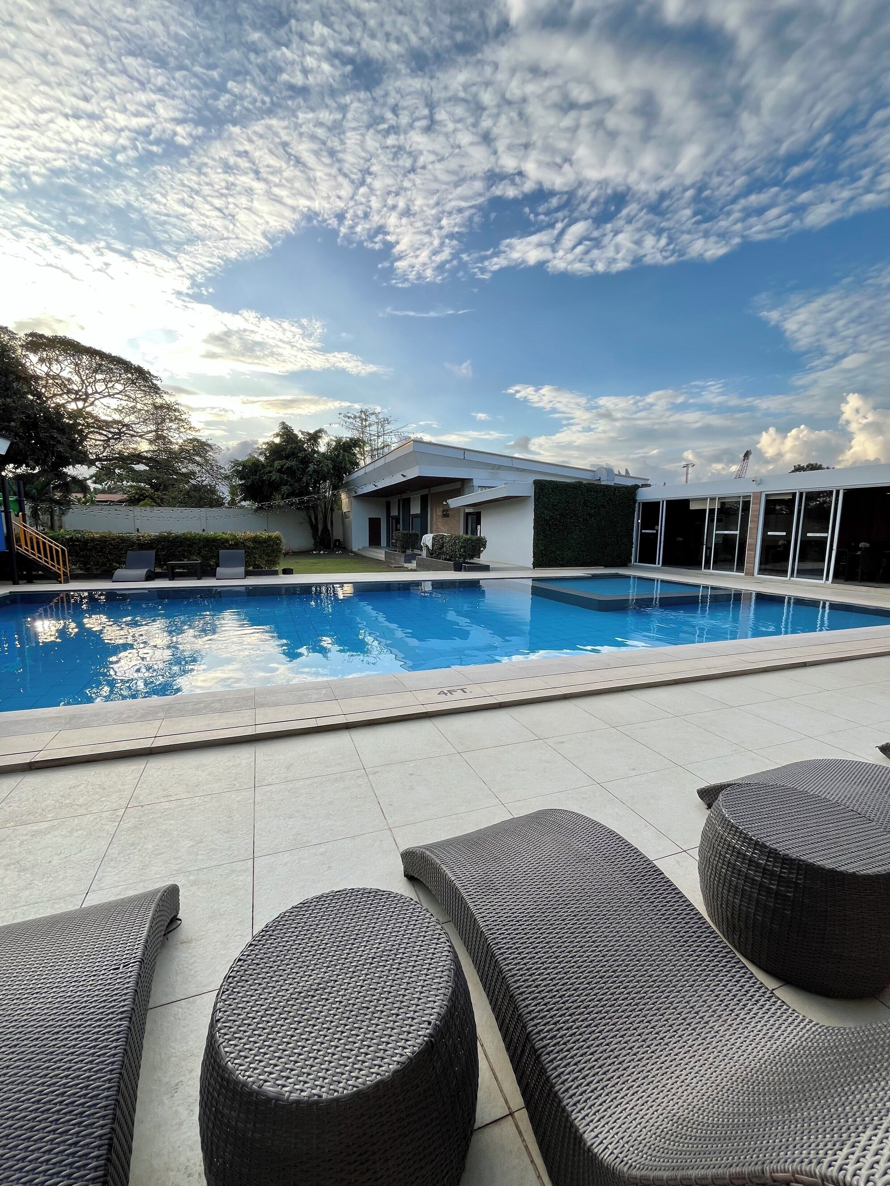 Un área de piscina moderna con un cielo azul despejado, una piscina y sillas de descanso.