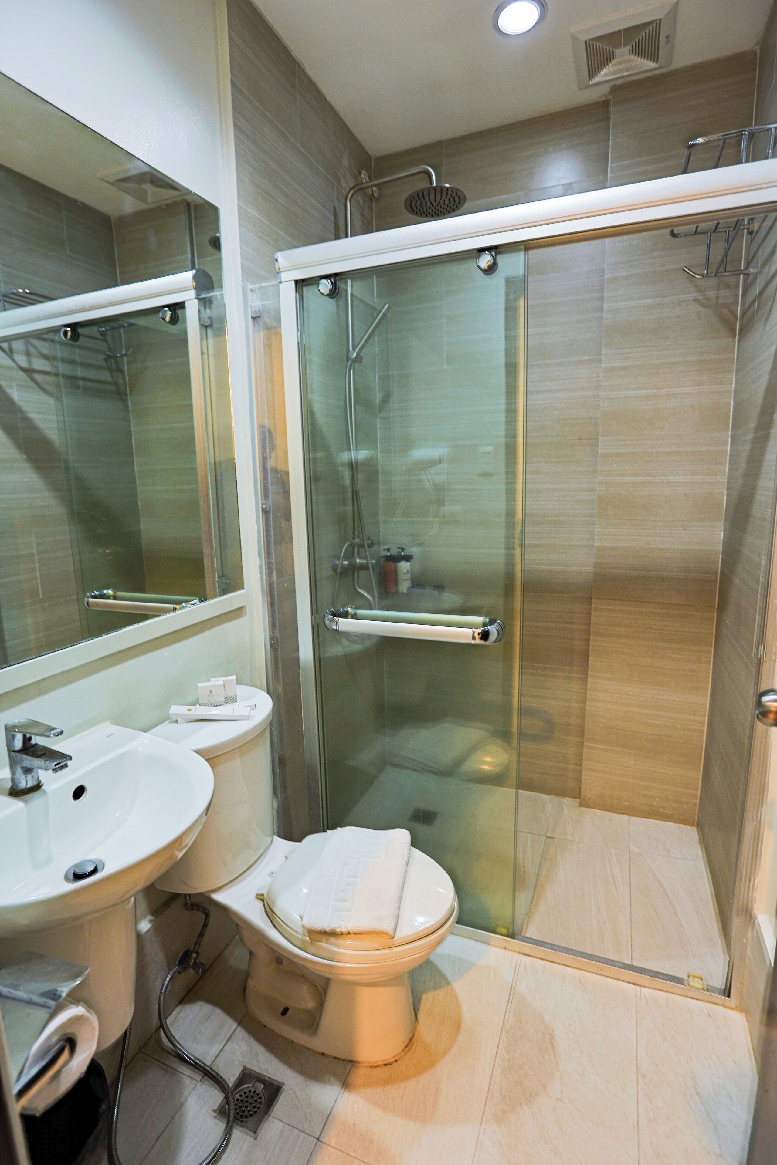 A modern bathroom with a glass-enclosed shower, a toilet, and a sink.