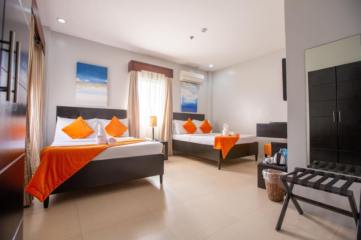 Een hotelkamer met twee bedden, een televisie, een bureau en een raam met gordijnen.