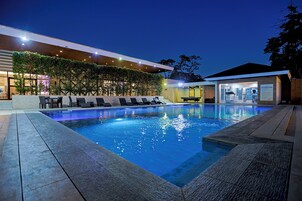 Una piscina al aire libre, sillones reclinables de piscina