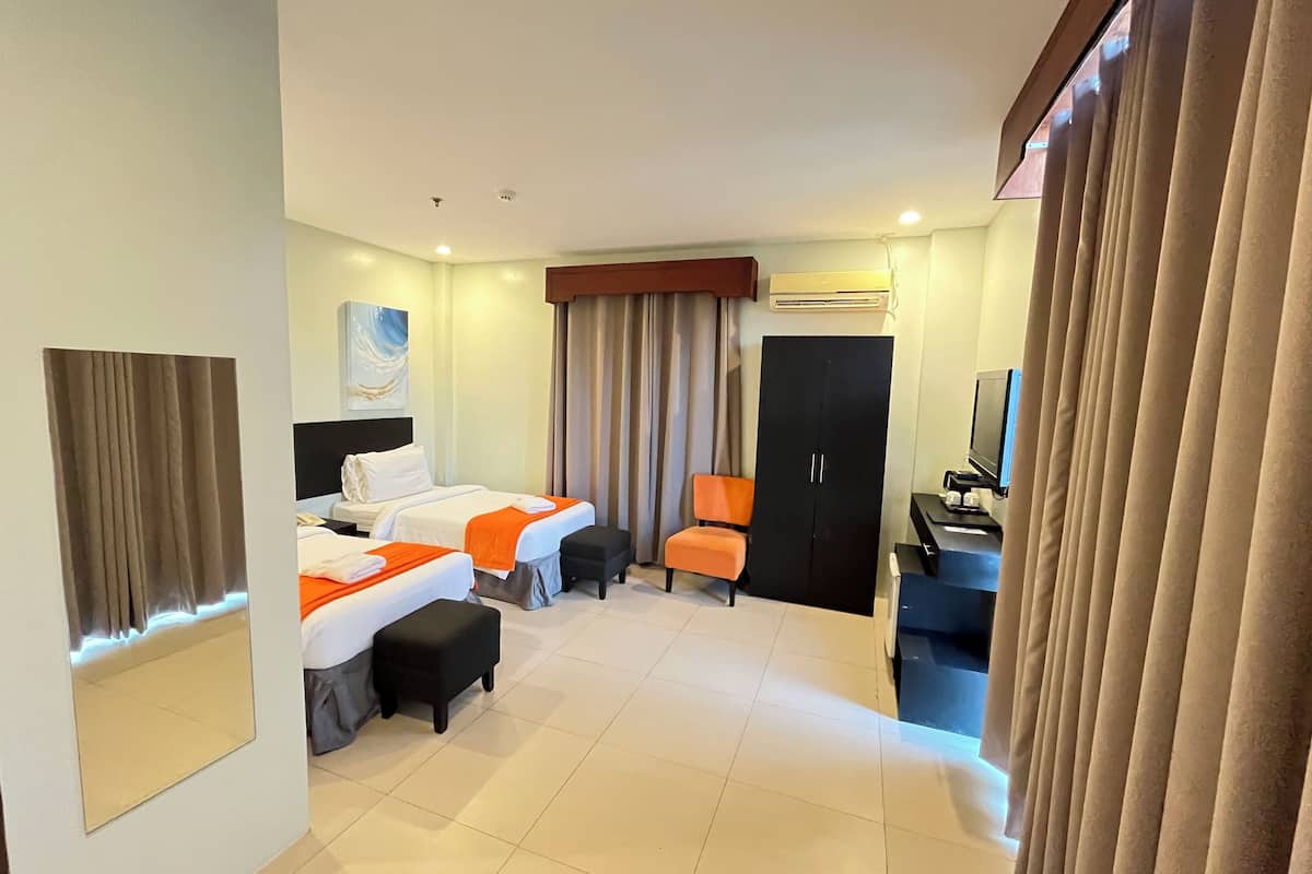 Een hotelkamer met twee bedden, een bureau, een stoel, een kledingkast en een televisie.